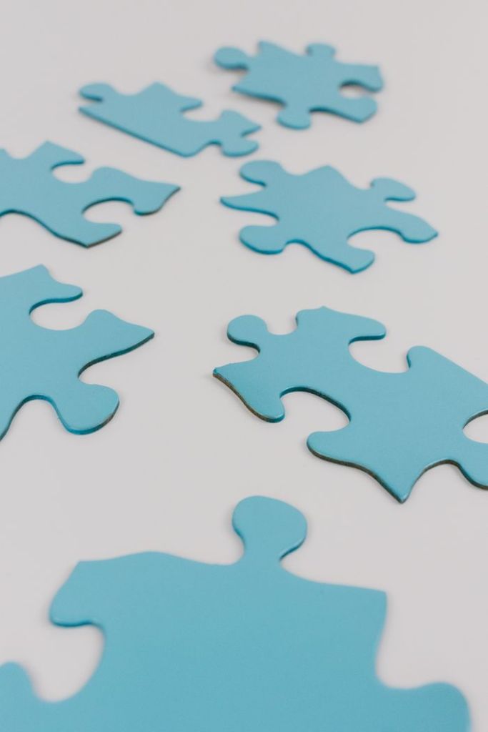 Close-up of blue puzzle pieces on a white surface, concept of problem-solving and integration.